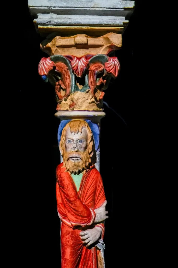 Vue d’ensemble des arcades reconstituées avec projection mapping restituant les couleurs sur chapiteaux et statues-colonnes